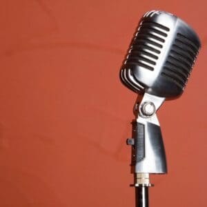 A microphone is on the stand in front of an orange wall.