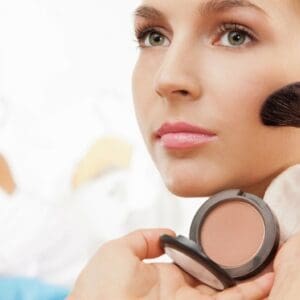 A woman holding a makeup brush in her hand.